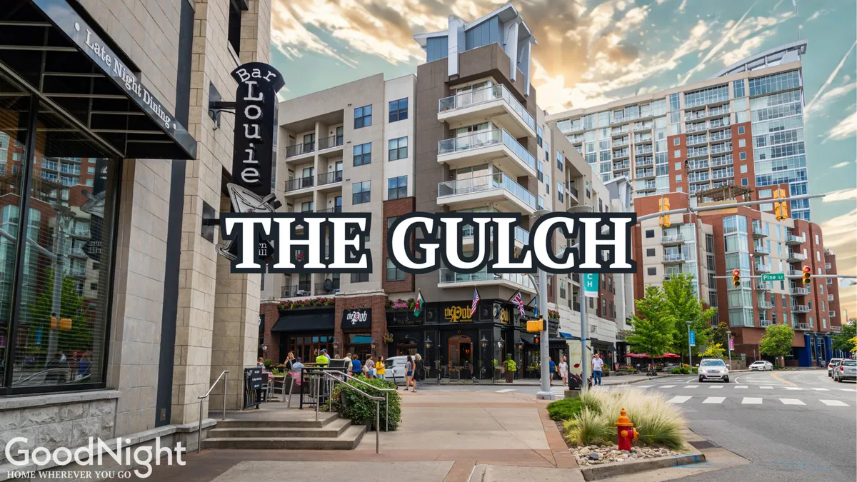 A bustling urban scene in The Gulch, featuring Bar Louie, The Gulch signage, modern apartments, and people enjoying the lively streetscape. The environment feels energetic and cosmopolitan, hinting at the nearby celebrated restaurants, nightlife, and cultural events.