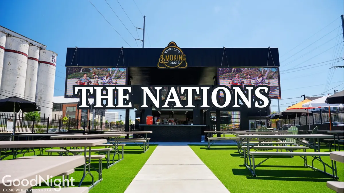An inviting exterior BBQ grill area with comfortable outdoor seating and 'The Nations' sign, set up for social gatherings and communal dining. The scene exudes a lively, welcoming mood perfect for get-togethers.
