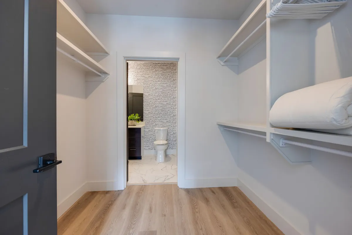 A view of the entryway area highlighting open closet space, accessible shelving for storage, and a doorway leading to the bathroom. The layout is organized and functional, ideal for efficient daily routines.